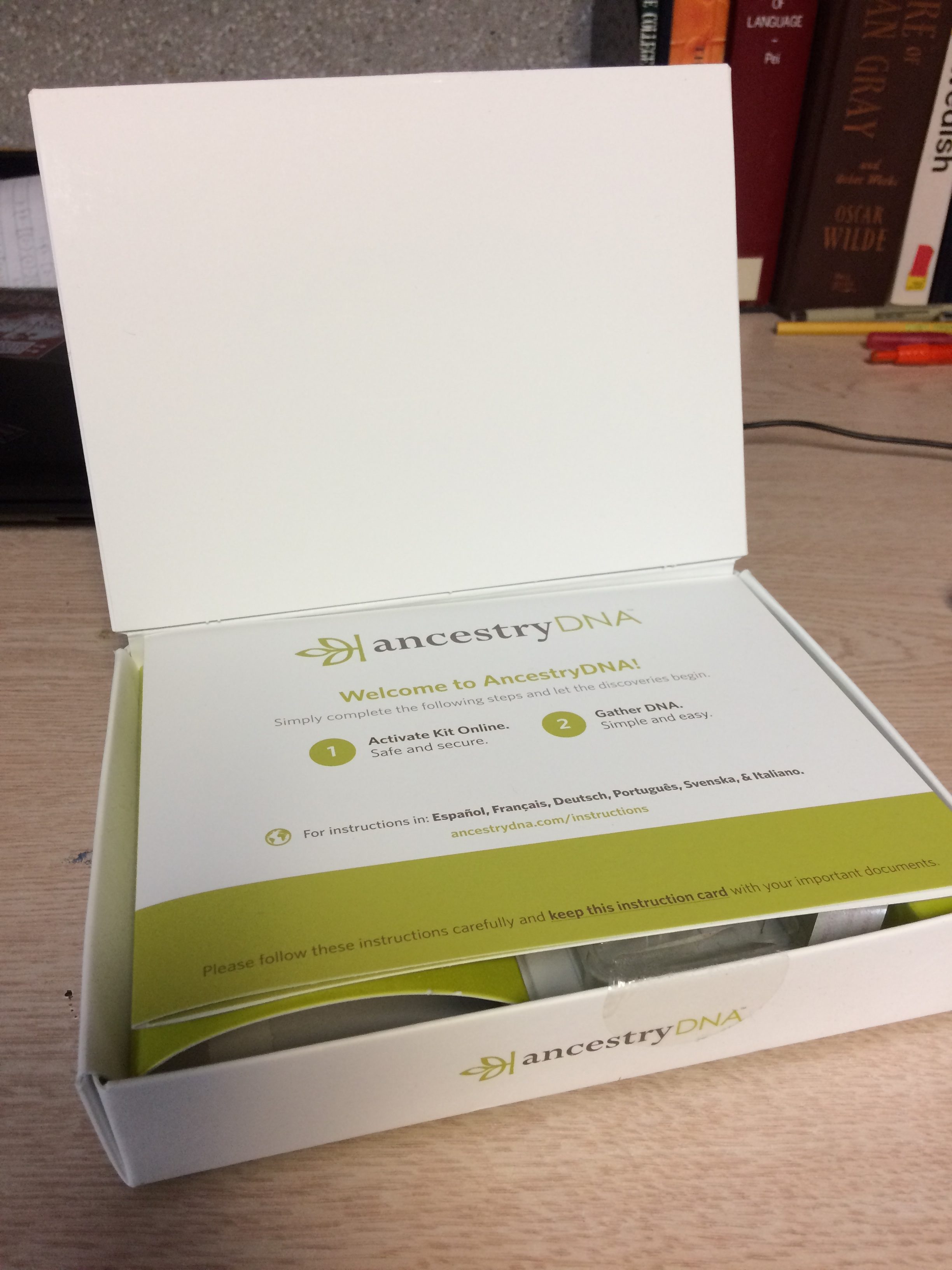 Photo of an Ancestry DNA kit on a desk with books in the background