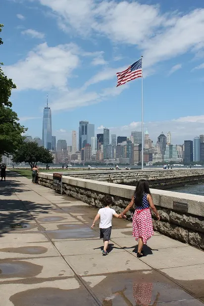 View of American flag on Ellis Island and two small children walking towards it